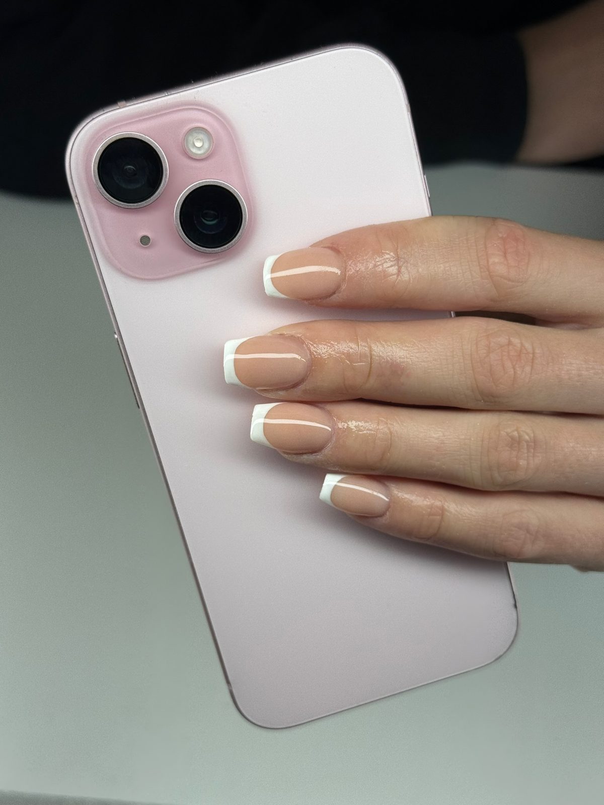 Witte French tips, hand om een roze telefoon